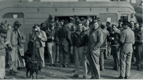 Historic black-and-white photograph of military personnel and local residents.