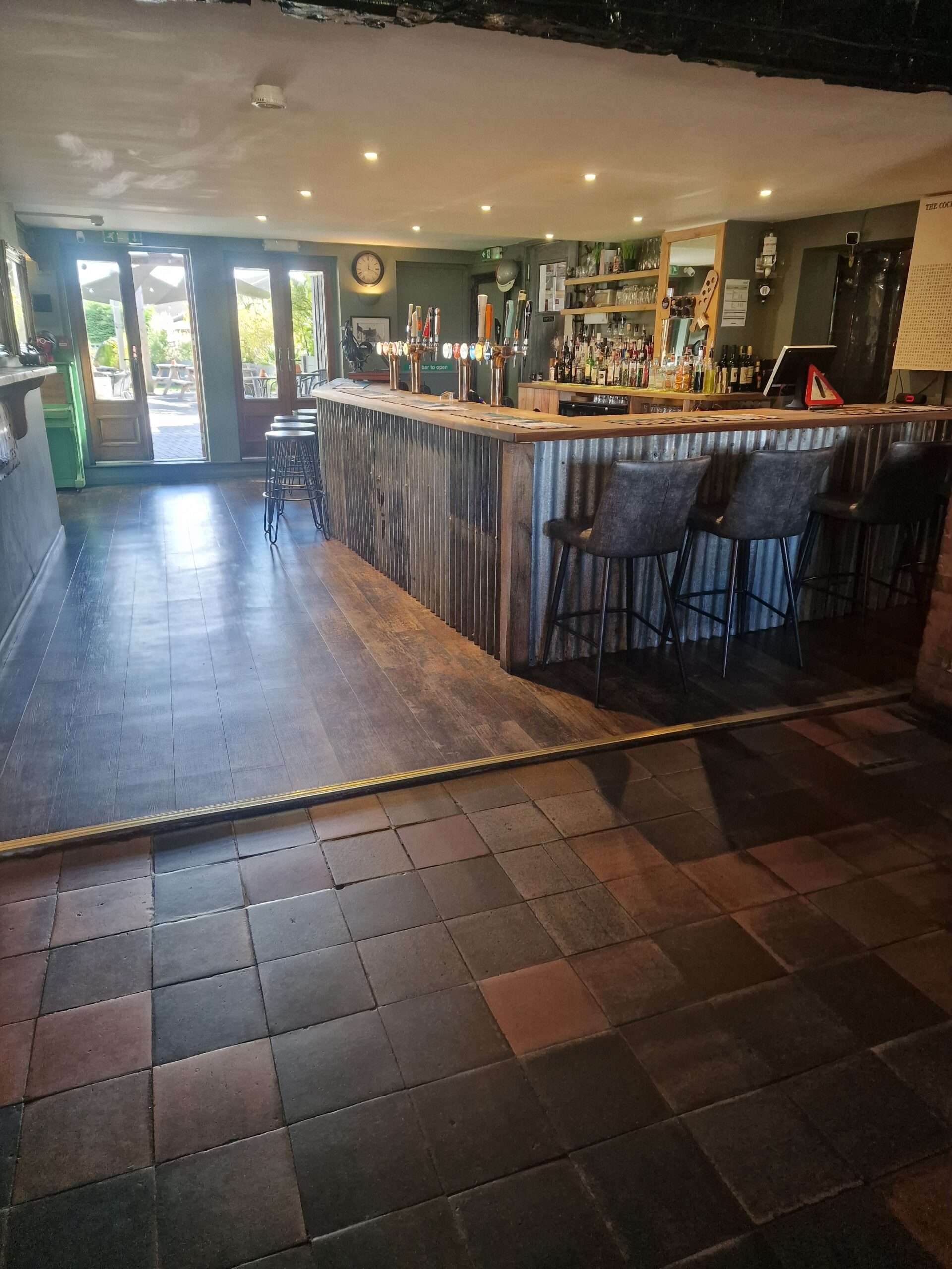 The Cock Inn Diss' interior featuring a spacious wooden bar, seating area and welcoming social space.