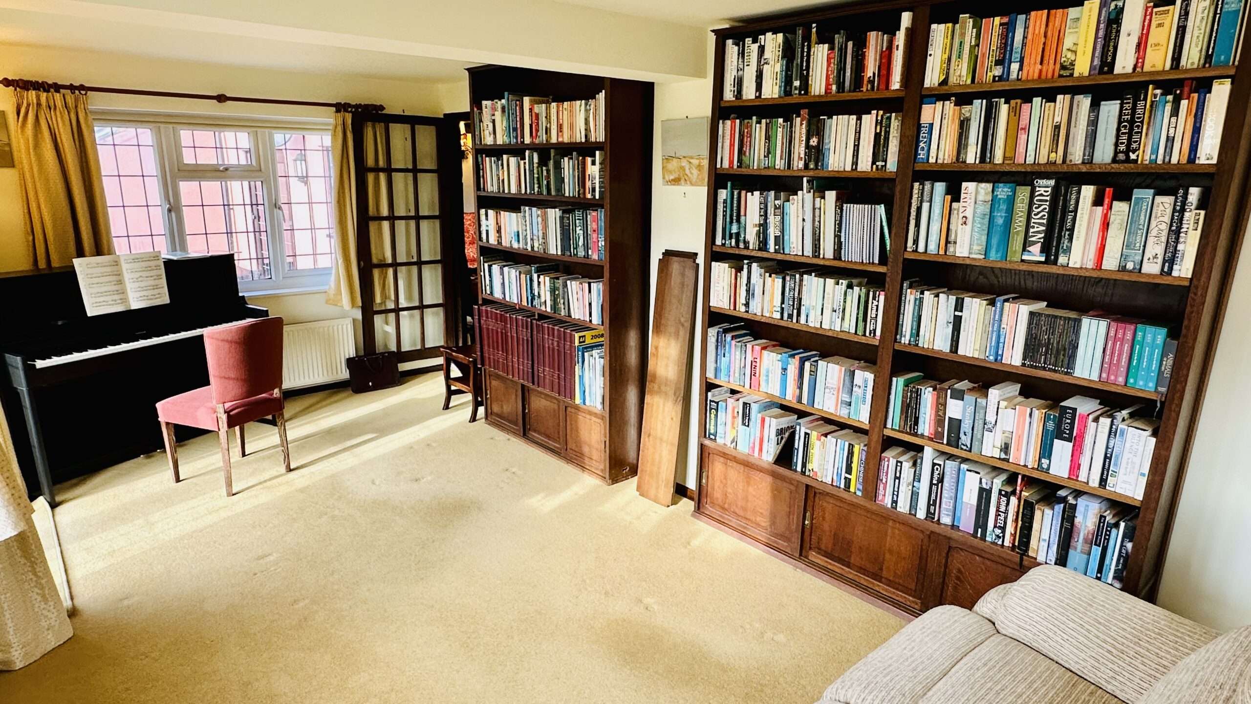 Danegels library room with bookshelves, piano and comfortable seating.