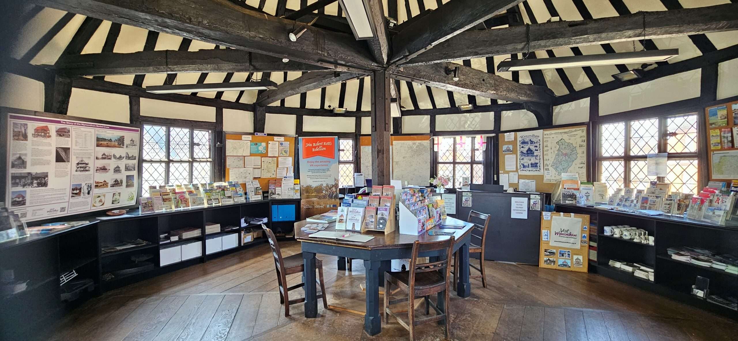 Interior of Wymondham Tourist Information Centre with visitor information displays, leaflet stands and exposed timber beams in a historic building.